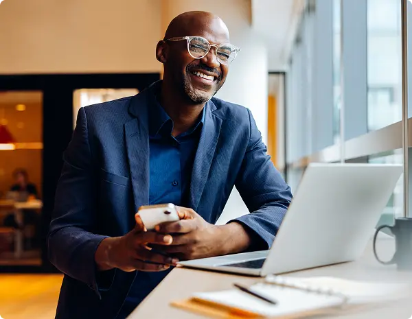 A man sitting at a laptop, smiling