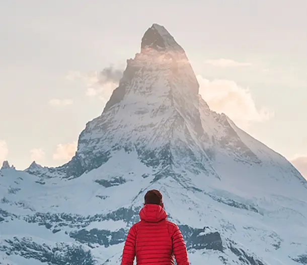 A man looking up to a snowy mountain peak in the distance